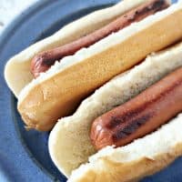 Hot dog cut ends in buns on blue plate with blurred background