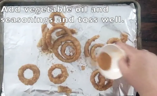 Small white bowl pouring out seasonings onto the baking sheet