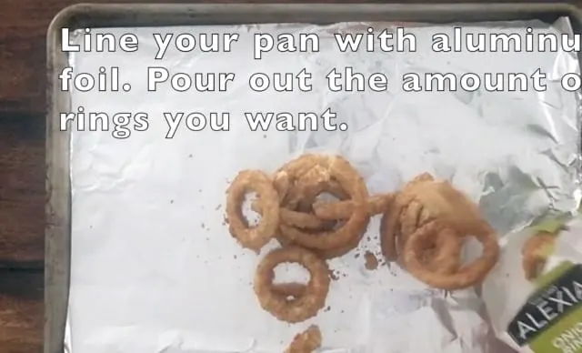 Frozen onion rings on a baking sheet lined with aluminum foil