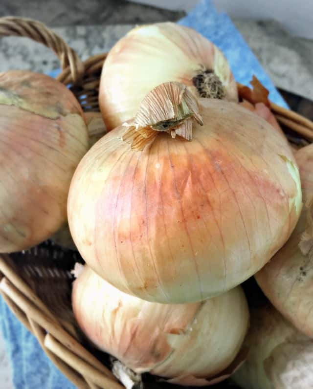 basket of onions with a peachy glow to the skin