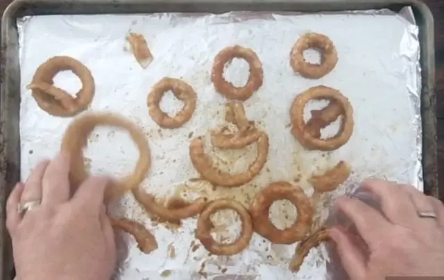 hands spreading the onion rings out for baking