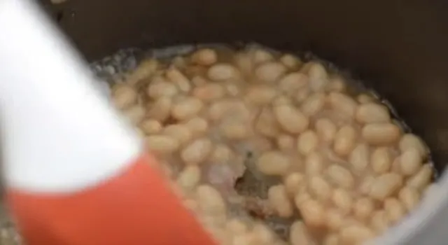 The navy beans added to the sauce pan