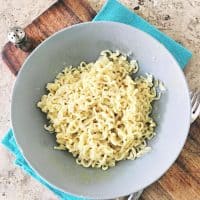 gray bowl of ramen with blue napkin and cutting board