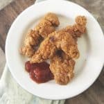 Overhead photo of three chicken strips on a white plate