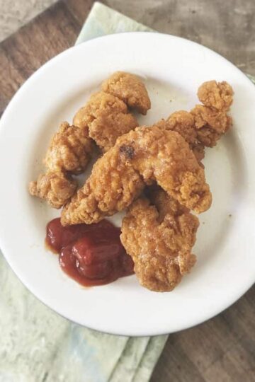 Overhead photo of three chicken strips on a white plate