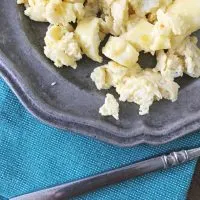 close up of scrambled eggs on the edge of gray plate