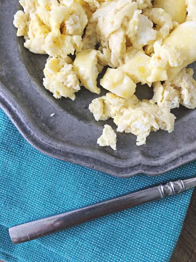 close up of scrambled eggs on the edge of gray plate