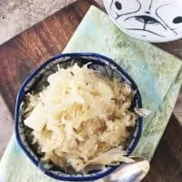 overhead shot of german sauerkraut in blue bowl, napkin, spon and extra bowl