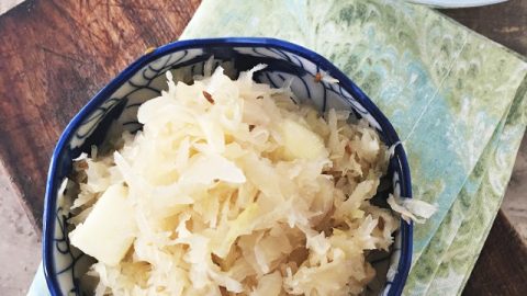 overhead shot of german sauerkraut in blue bowl, napkin, spon and extra bowl