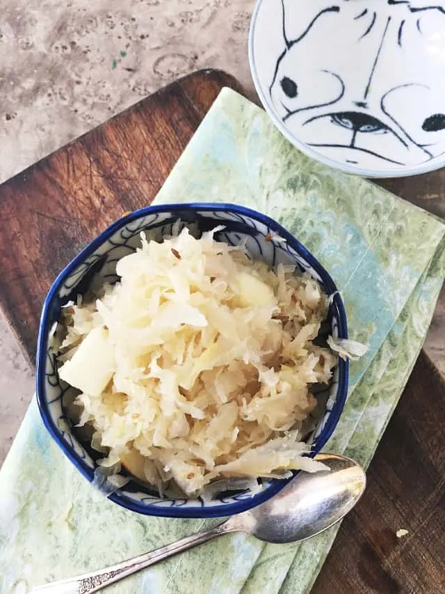 overhead shot of german sauerkraut in blue bowl, napkin, spon and extra bowl