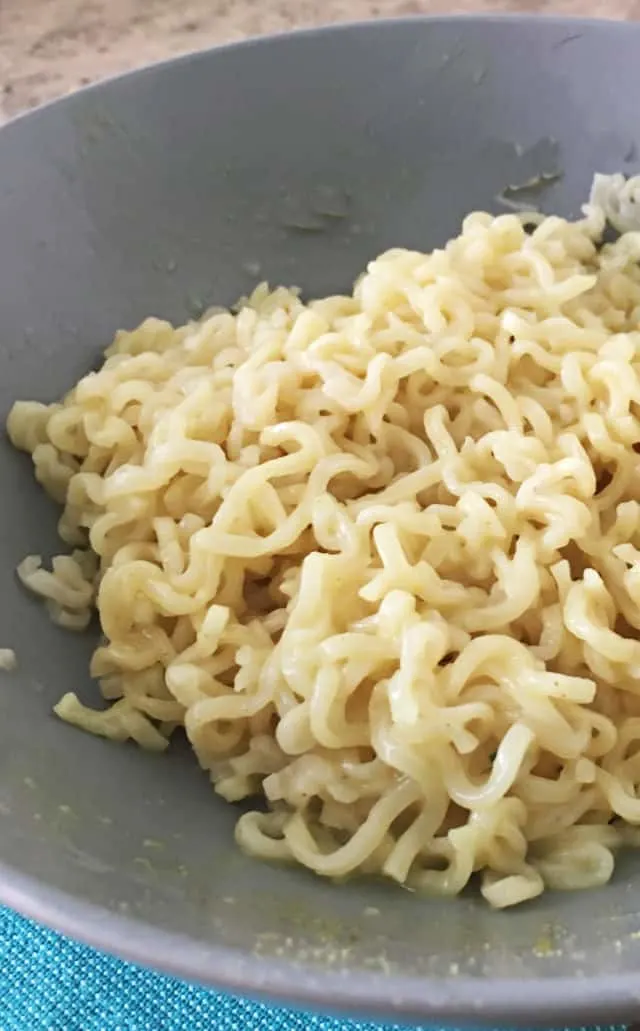 close up shot of ramen noodles in a gray bowl with blue napkin
