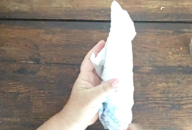 ear of corn wrapped in paper towel held by a hand