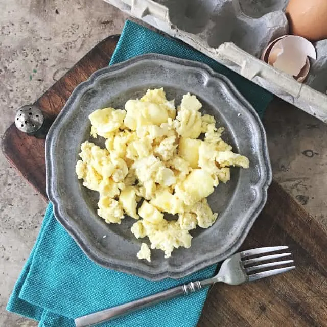 overhead view of gray plate with microwave scrambled eggs and egg carton