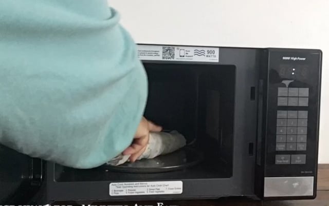 hand putting ear of corn in the microwave