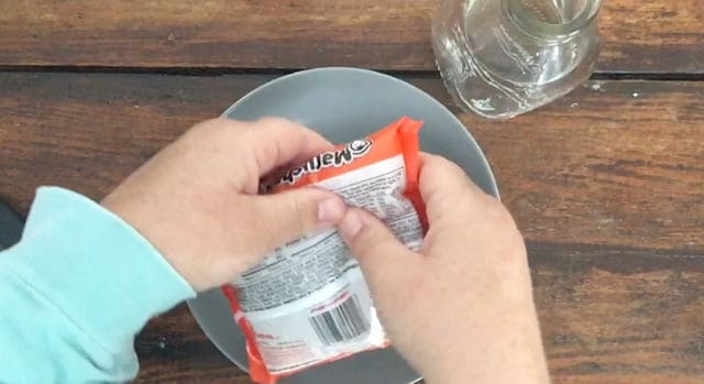 two hands breaking up a package of ramen noodles