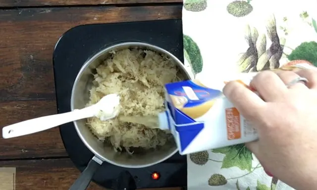 adding chicken stock to the saucepan of German Sauerkraut