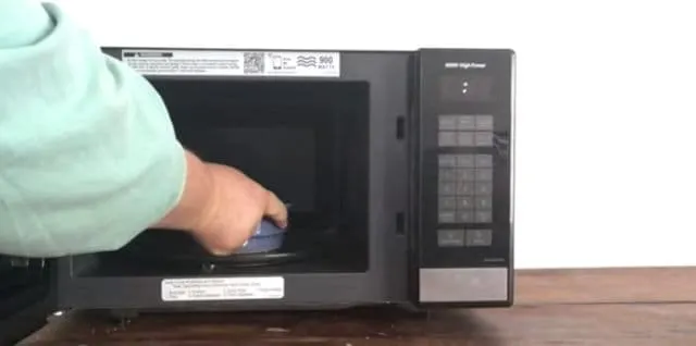 hand placing blue bowl in microwave