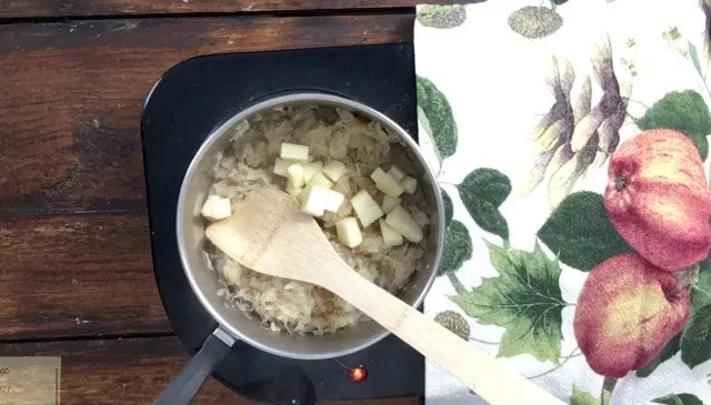 wooden spoon in saucepan for how to make canned sauerkraut