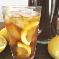 Clear glass of southern lemon iced tea with lemons floating in it.