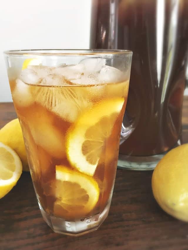 Clear glass of southern lemon iced tea with lemons floating in it.