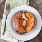 overhead photo of an orange sweet potato on a white plate with green napkin