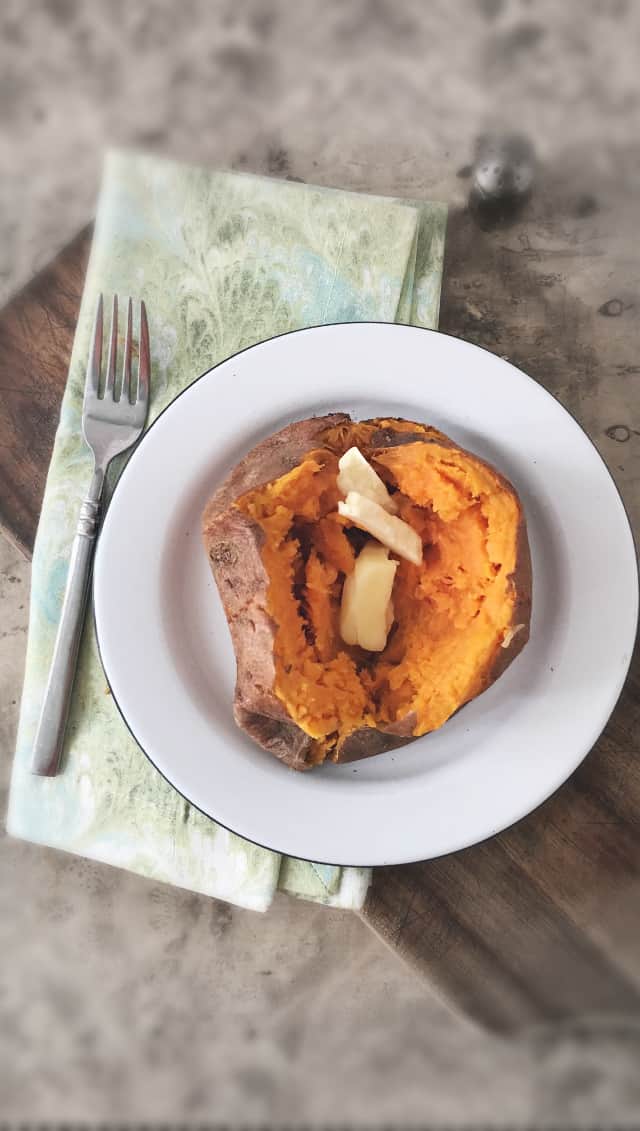 overhead photo of an orange sweet potato on a white plate with green napkin