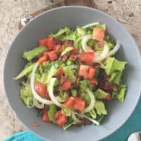 overhead shot of southern wilted lettuce salad in gray bowl with blue napkin