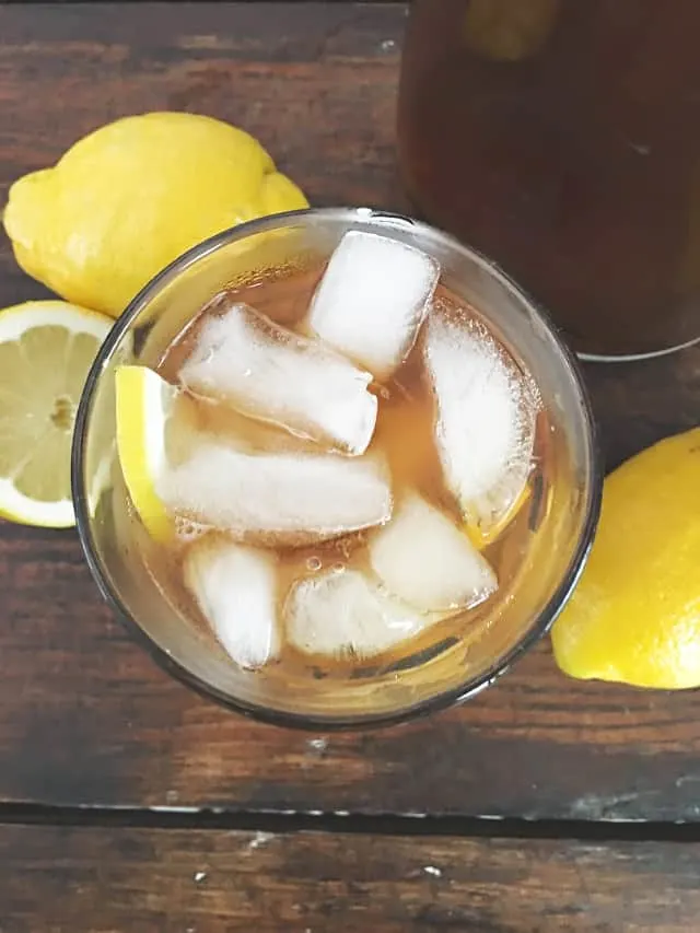 view overhead of a glass of iced tea with lemons in background