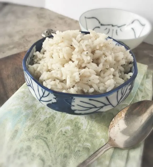 side view shot of a blue bowl of rice on a green napkin with spoon
