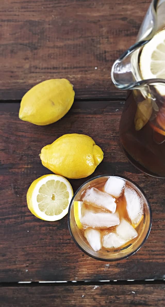 glass, pitcher and two and a half lemons on wood table