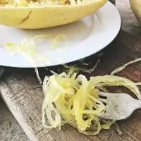 Spaghetti Squash Strands on a fork sitting on cutting board