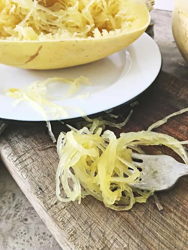 Spaghetti Squash Strands on a fork sitting on cutting board