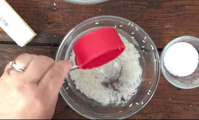 measuring cup adding water to a bowl of rice