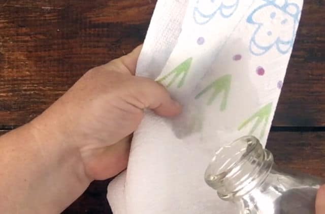 hand holding a paper towel while water being poured from a bottle