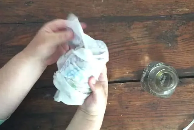 two hands wrapping a potato in a paper towel