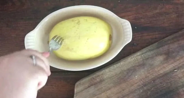 Fork piercing the skin of the microwaved spaghetti squash