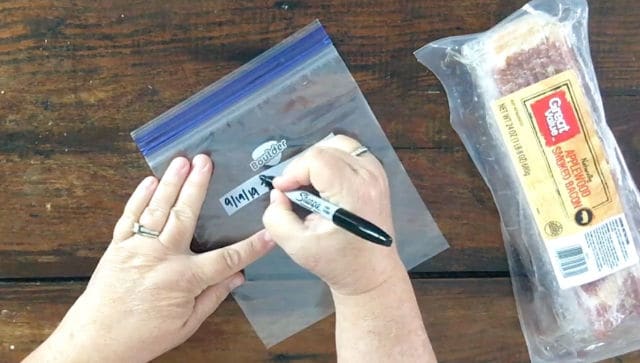 hand labeling freezer bag with sharpie marker and bacon