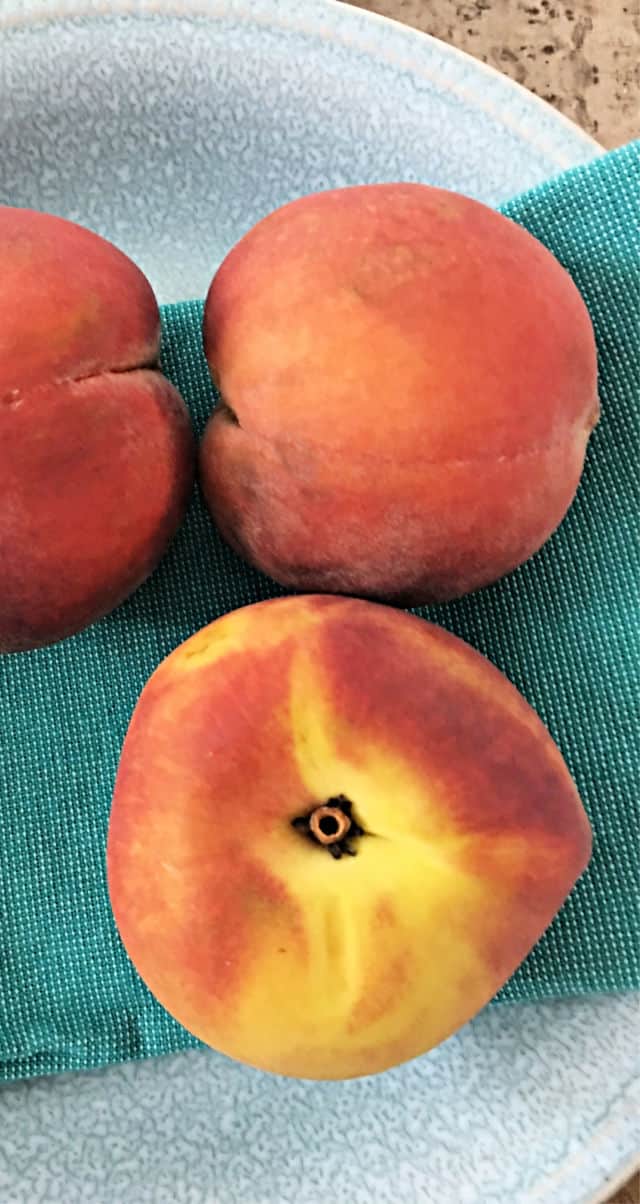 three fruits on a blue napkin in gray bowl