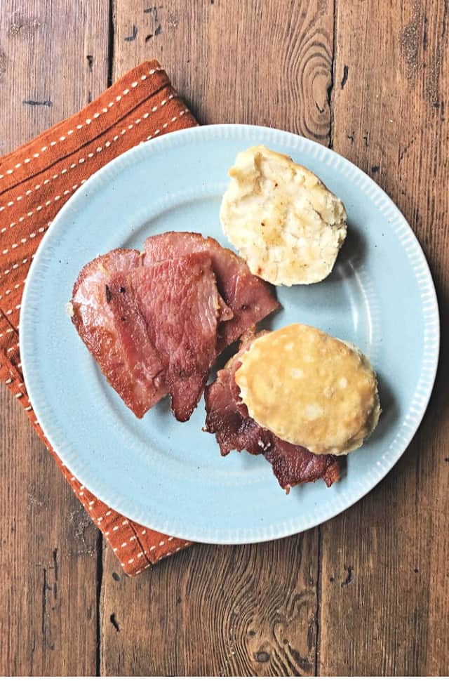 Open face country ham biscuit and one closed on blue plate