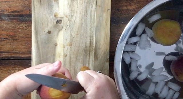 using a paring knife to peel the skin off the peach