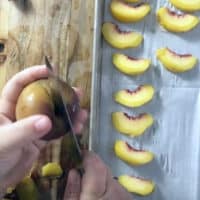 using a paring knife to cut a peach in half, peach slices on the side