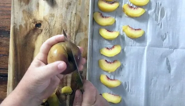 using a paring knife to cut a peach in half, peach slices on the side