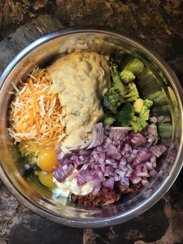 silver bowl holding the ingredients for cheesy broccoli casserole