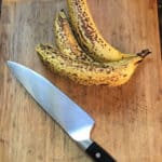 bananas on cutting board with a knife