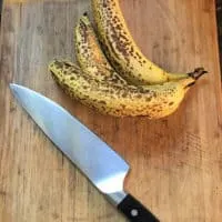 bananas on cutting board with a knife