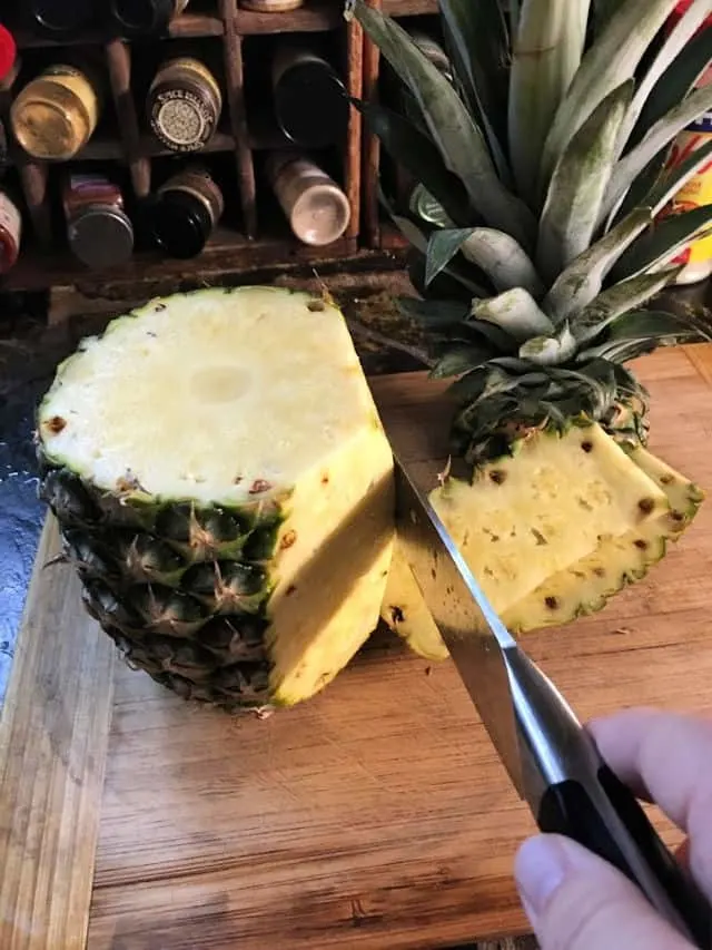A knife cutting down the side of a pineapple