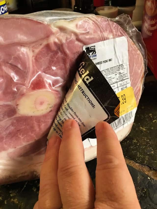 fingers pulling a label back on a ham