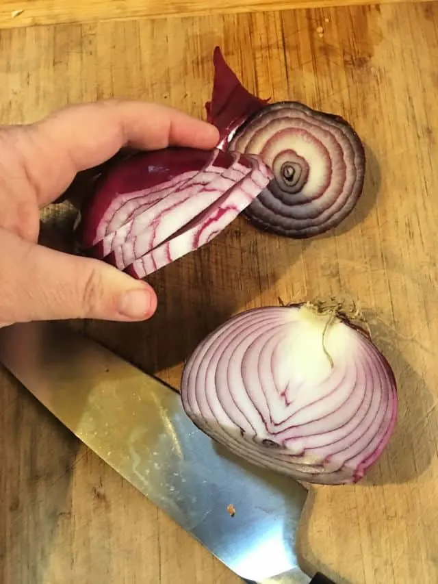 hand holding onion cut at side into slabs