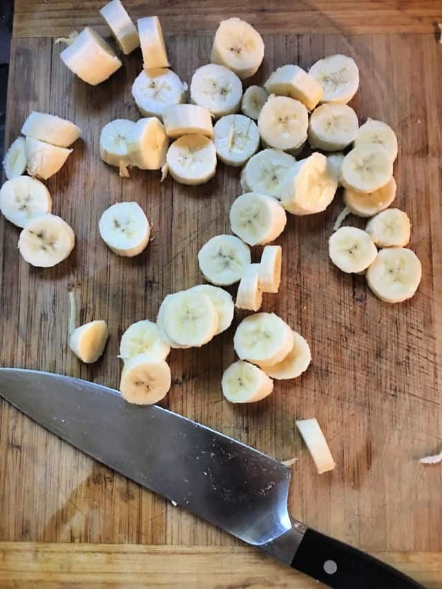 Bananas cut into disks on cutting board with knife