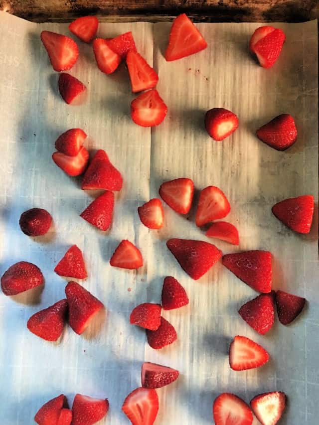 Berries spread on baking sheet with parchment paper beneath